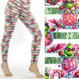 Festive leggings with green Grinch-like character lounging in pink cocktail glasses on a pink and white striped background with candy canes and fruit by Nikki Whoops Boutique.
