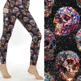Leggings featuring vibrant gemstone skulls in pink, blue, and gold hues against a glittering black background.