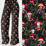Wide leg lounge pants featuring chibi-style horror characters dressed as Santa Claus with candy canes, balloons, and Christmas trees on a black starry background by Nikki Whoops Boutique.