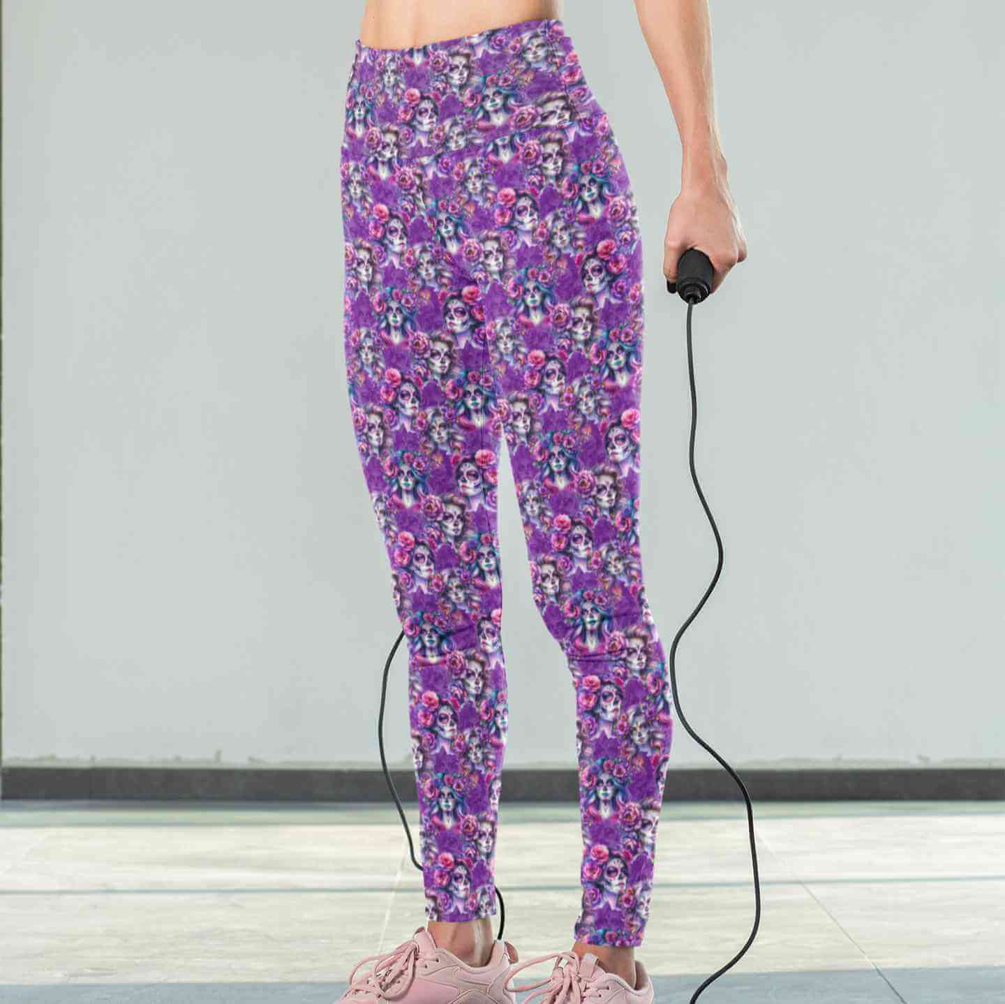 Mockup of lady wearing of Violet Femmes leggings. La Catrina images with flowing hair with tints of pink, mauve and blue. vibrant pink and purple flowers in their hair on a rich purple background by Nikki Whoops Boutique.