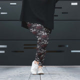 Person wearing floral leggings with a black coat and white sneakers against a dark background