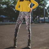 Person wearing a yellow sweater and colorful day of the dead leggings standing on a street.
