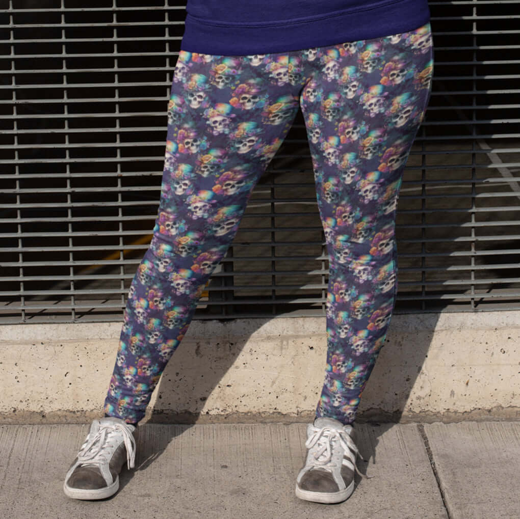 girl wearing leggings featuring a floral and skull pattern, with an assortment of hats and vibrant rainbow roses on the brims of the skulls.