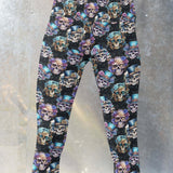 girl wearing leggings featuring a steampunk skull design with colorful skulls adorned with top hats and roses, set against a black background.