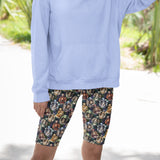 Person wearing a light blue hoodie and patterned shorts with a blurred outdoor background