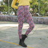 Person wearing colorful skeleton leggings featuring witches drinking cocktails and a yellow top outdoors.