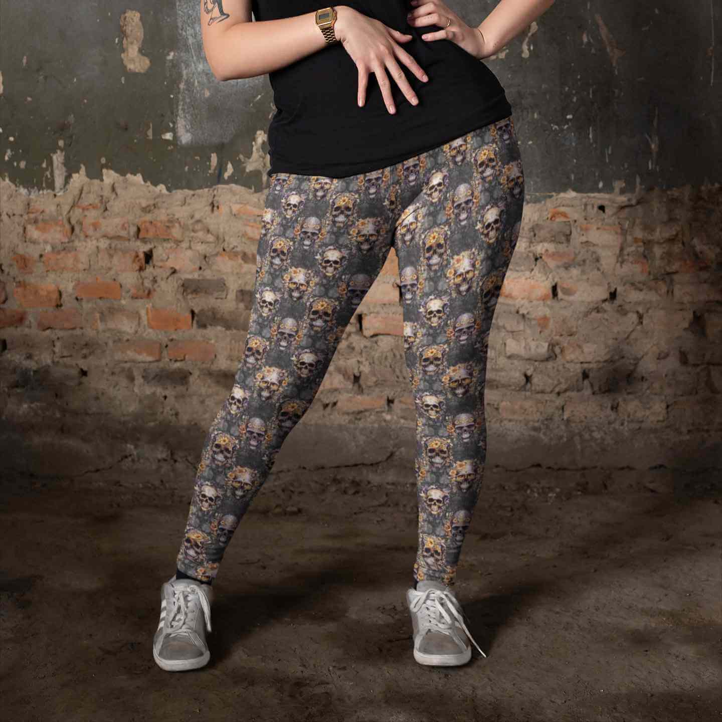 Gilded Grunge Skull Leggings featuring gold-detailed skulls with intricate filigree and floral embellishments on a grunge-inspired dark background. gilded-grunge-leggings-mockup-of-a-tattooed-woman-wearing-plus-size-leggings-against-an-old-wall