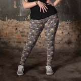 Gilded Grunge Skull Leggings featuring gold-detailed skulls with intricate filigree and floral embellishments on a grunge-inspired dark background. gilded-grunge-leggings-mockup-of-a-tattooed-woman-wearing-plus-size-leggings-against-an-old-wall