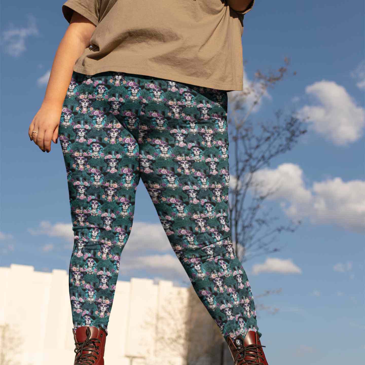 Person wearing Day of the Dead patterned leggings and brown boots, posing outdoors against a blue sky.