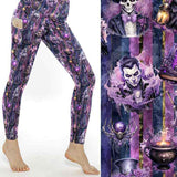 Purple patterned Halloween leggings worn by a person on a white background, with a decorative panel featuring a gothic-themed design.