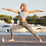Woman practicing yoga on a dock with boats in the background