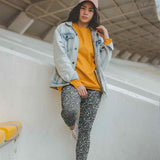 Person wearing a yellow shirt, denim jacket, and leopard print leggings standing on a staircase.