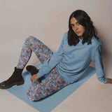 Seated lady wearing Unicorn print leggings featuring quirky, colourful unicorns with tea cups, checkerboards and wild patterns inspired by Alice in Wonderland.
