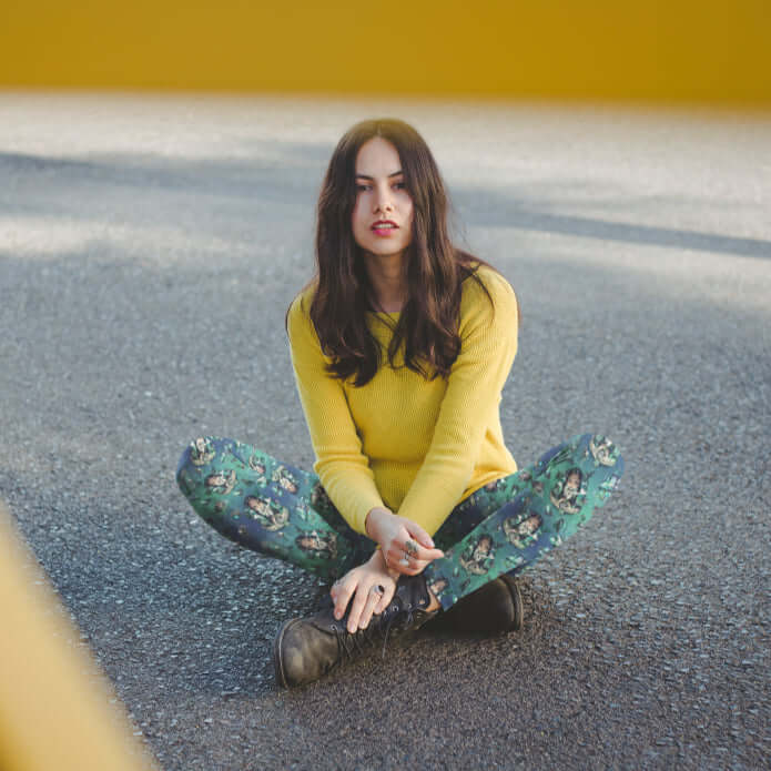lady sitting on the ground wearing Wednesday Addams: Over Your Dead Body leggings by Nikki Whoops Boutique.