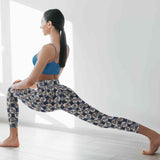 Woman in blue sports bra and patterned leggings performing a yoga pose in a bright room.