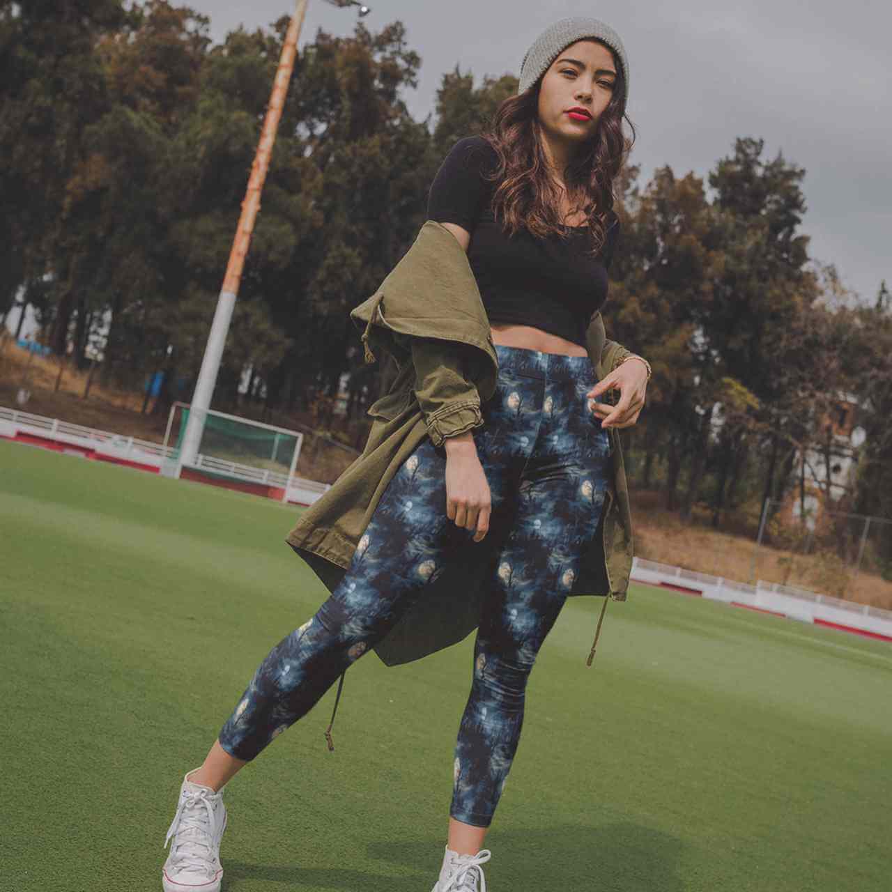 Woman wearing Sleepy Hollow Full-Length Leggings featuring moonlit cottages, dark forests, glowing windows, twisted trees and atmospheric gothic landscape artwork.