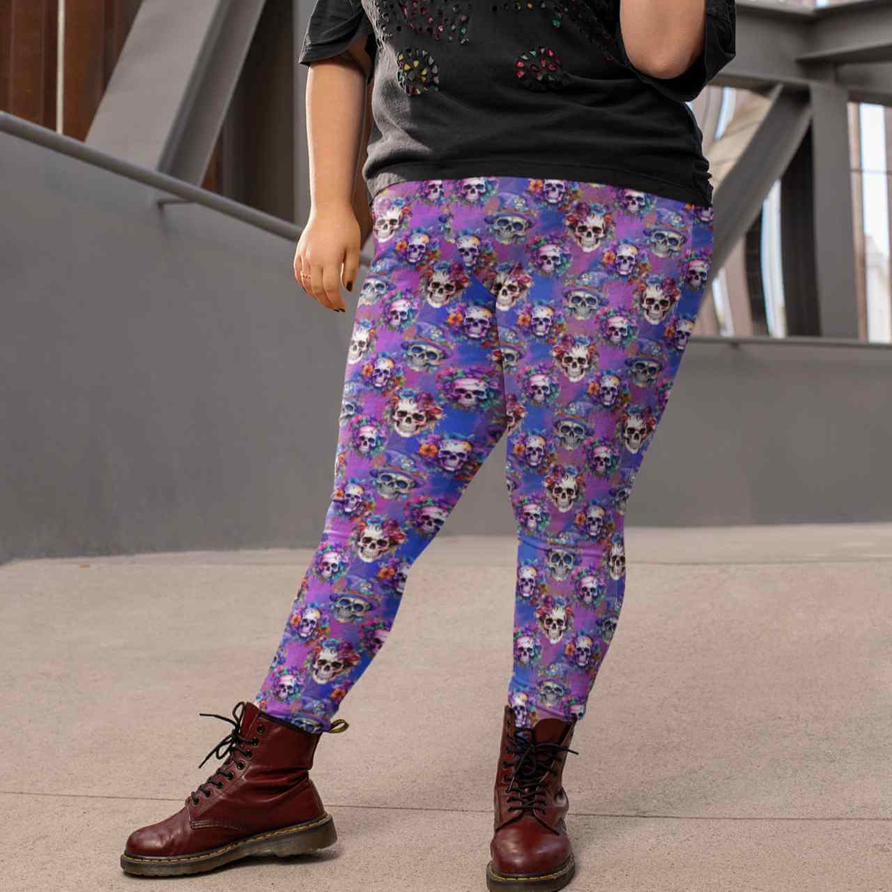 Person wearing 'Til Death Do We Party Skull Leggings colorful skull-patterned leggings and brown boots, standing outdoors in an urban environment by Nikki Whoops Boutique.