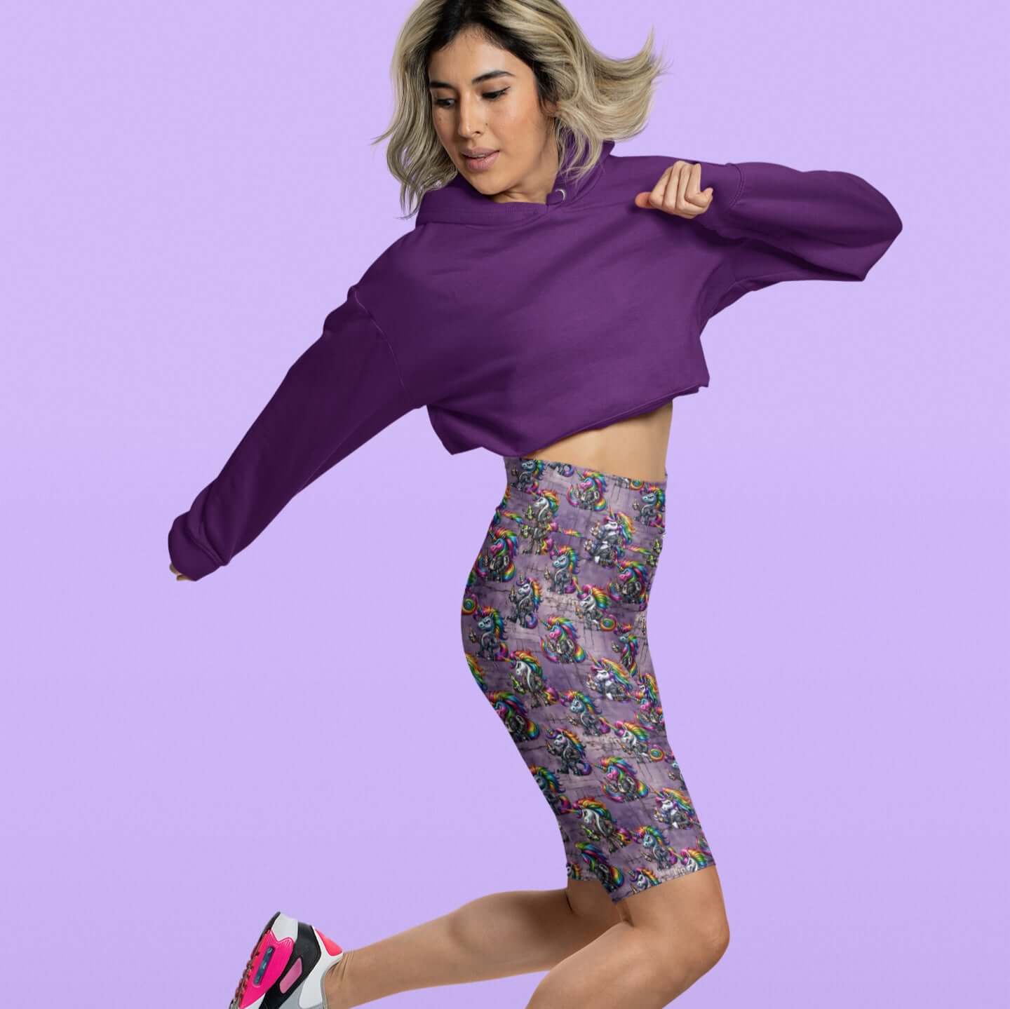 Woman wearing a purple cropped hoodie and patterned leggings on a light purple background