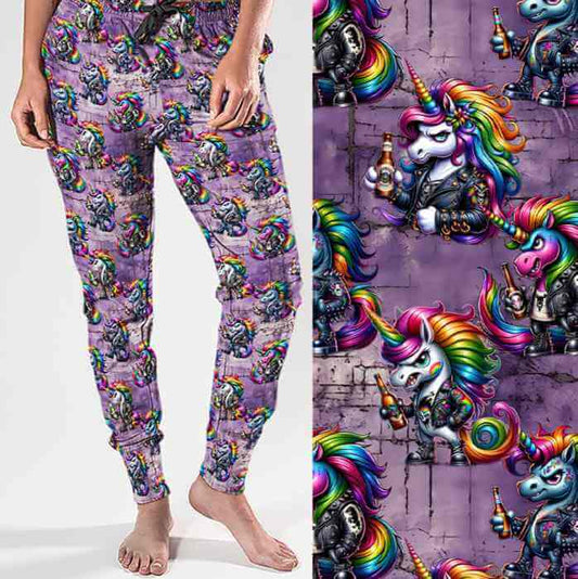 mockup of Full-length jogger pants with a bold print featuring punk-style unicorns with rainbow manes, leather jackets, studs and beer bottles. The background is a grungy purple brick wall for added edge.