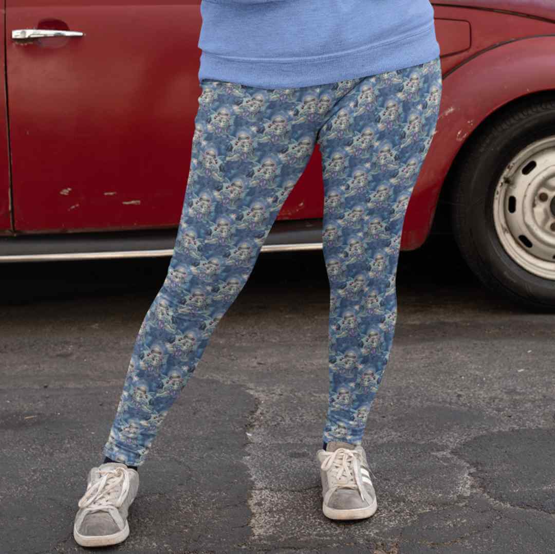 mockup-of-a-daring-woman-wearing-leggings-and-a-sweatshirt Wintry Dragonling Strangelings Leggings featuring an ethereal gothic-eyed fairy holding a baby dragon, set against a magical winter night sky in deep blues and lilac. by Nikki Whoops Boutique.