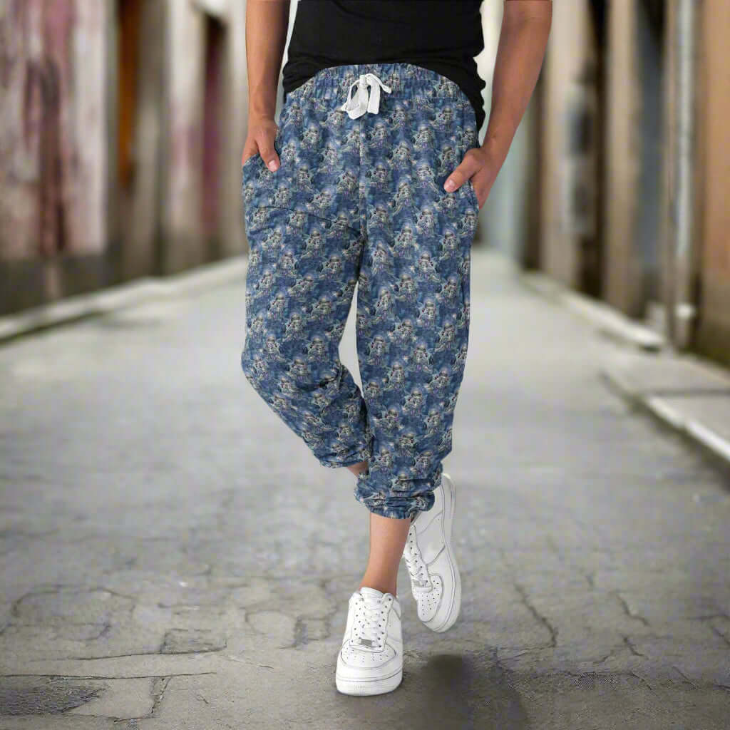 Woman wearing capri joggers in Wintry Dragonling Strangelings capri joggers from artist Jasmine Beckett-Griffith featuring an ethereal gothic-eyed fairy holding a baby dragon, set against a magical winter night sky in deep blues and lilac by Nikki Whoops