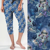mockup of Wintry Dragonling Strangelings capri joggers from artist Jasmine Beckett-Griffith featuring an ethereal gothic-eyed fairy holding a baby dragon, set against a magical winter night sky in deep blues and lilac by Nikki Whoops Boutique. Nikki Whoop