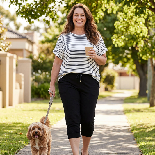 Woman wearing black capri jogger pants walking a dog