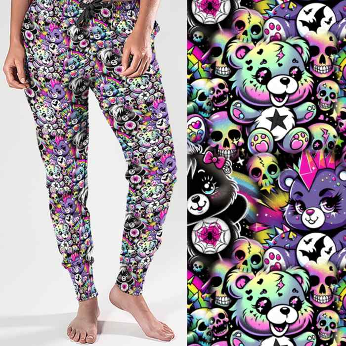 Full length jogger pants featuring colourful punk-inspired teddy bears, rainbow skulls, bats, spiderwebs and neon alternative artwork on a black background with bright pink, purple, green and blue accents.