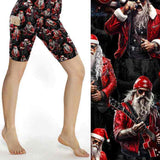 Black Christmas sports shorts with tattooed rock-star Santa in red leather jacket surrounded by guitars and microphones under stage lights by Nikki Whoops Boutique.