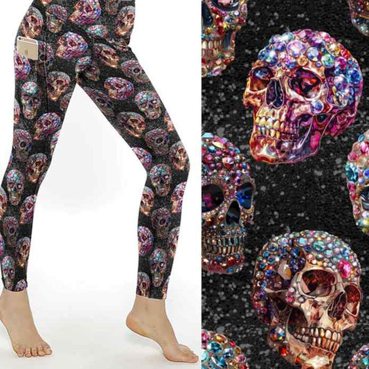 Leggings featuring vibrant gemstone skulls in pink, blue, and gold hues against a glittering black background.