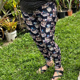 Person wearing leggings featuring a whimsical Victorian-inspired cat print, with a wide waistband and deep side pockets, standing on grass with plants in the background