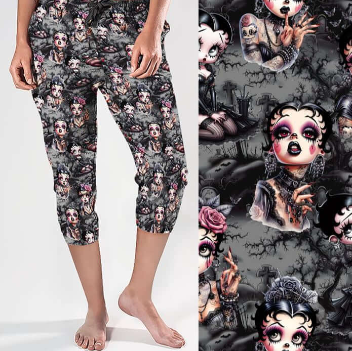 Capri jogger pants featuring a gothic cartoon print of heavily tattooed, pin-up inspired women with dramatic makeup. Background includes gravestones, thorny trees and a dark grey atmosphere.