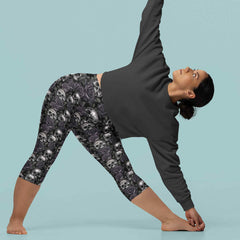 Black Death capri leggings. white and grey skulls on a background of black roses on a woman doing yoga.