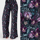 Wide leg lounge pants with dark floral print featuring purple and white orchids on a black background.