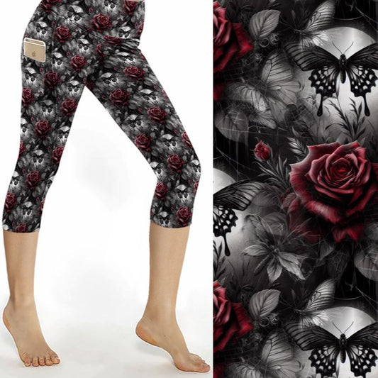 Capri leggings featuring glowing blue butterflies, skulls, and dark florals under a moody purple and black backdrop