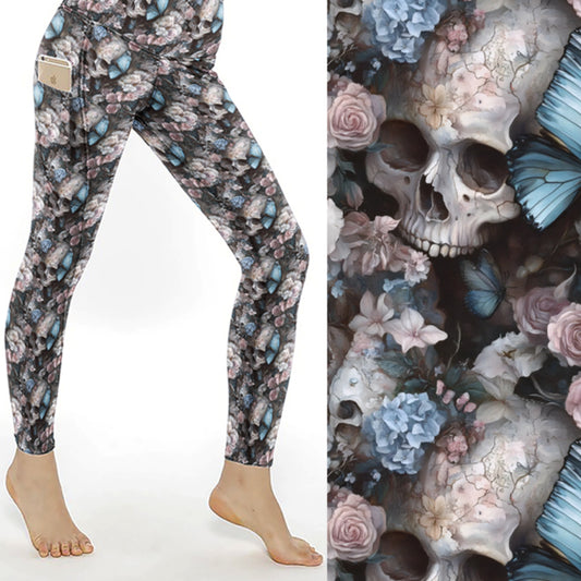 Leggings with cracked skulls, pastel flowers, and blue butterflies on a dark background.