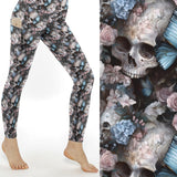 Leggings with cracked skulls, pastel flowers, and blue butterflies on a dark background.