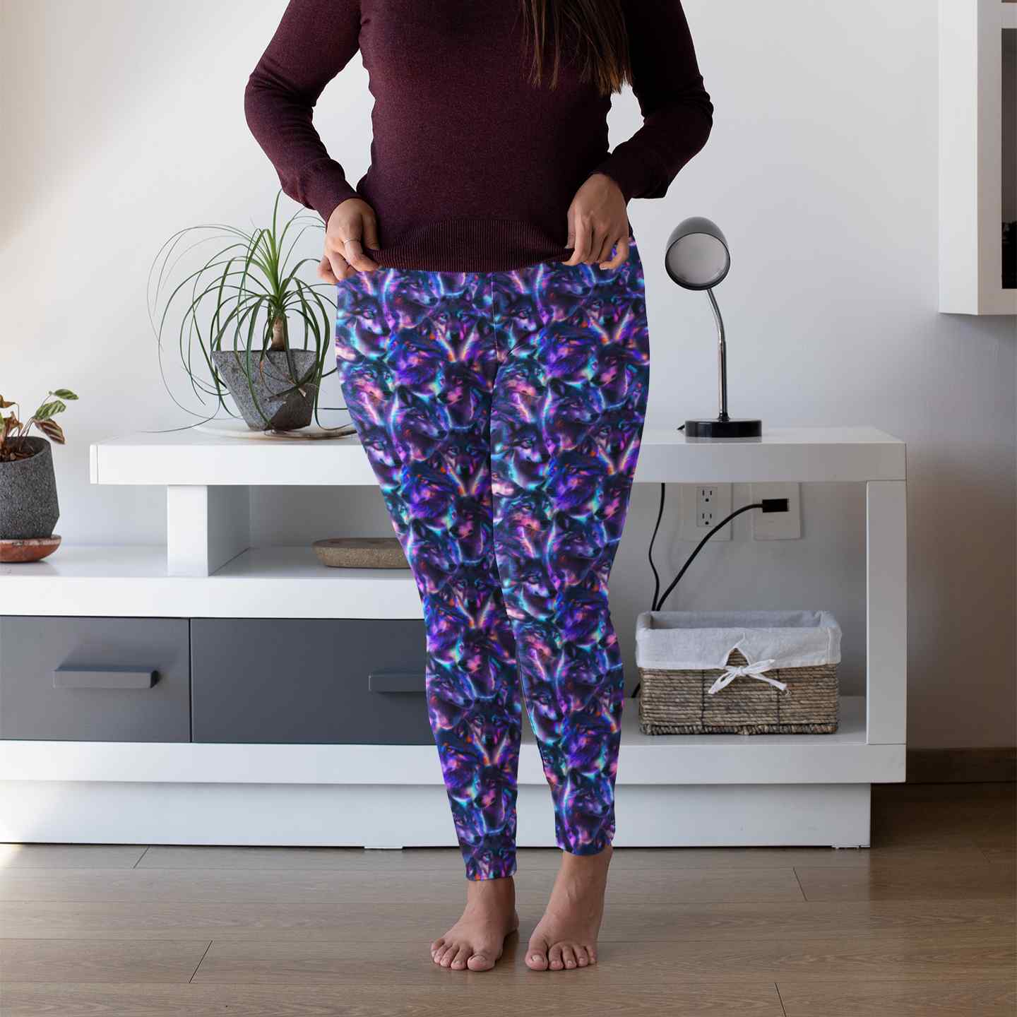 Person wearing colorful wolf patterned leggings in a room with a white cabinet and plants.