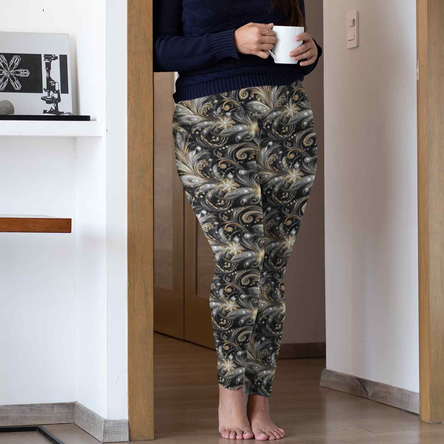 Person wearing gold and black leggings holding a cup in a home setting.