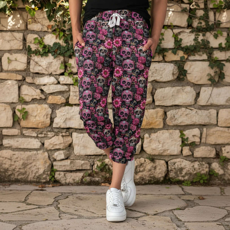 Person wearing pink and black floral skull patterned pants in front of a garden wall