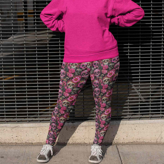 Person wearing a bright pink hoodie and patterned pants standing against a metal fence.