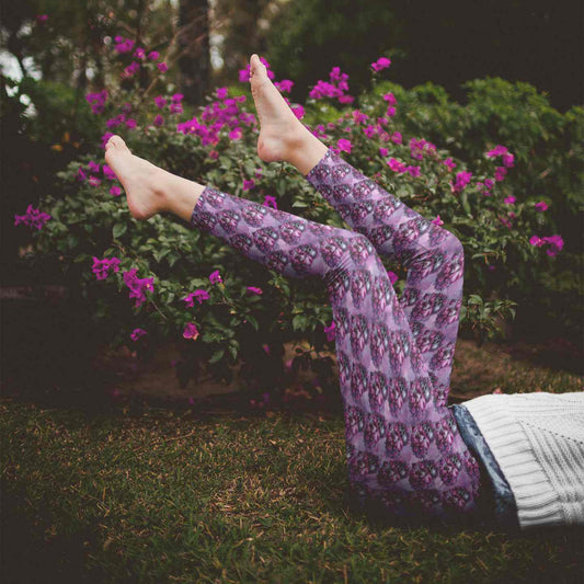 Person in purple skull leggings lying on grass with pink flowers in the background