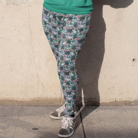 girl standing against a wall wearing leggings featuring a whimsical design with mermaids, sea creatures, and Day of the Dead-inspired makeup and garlands.