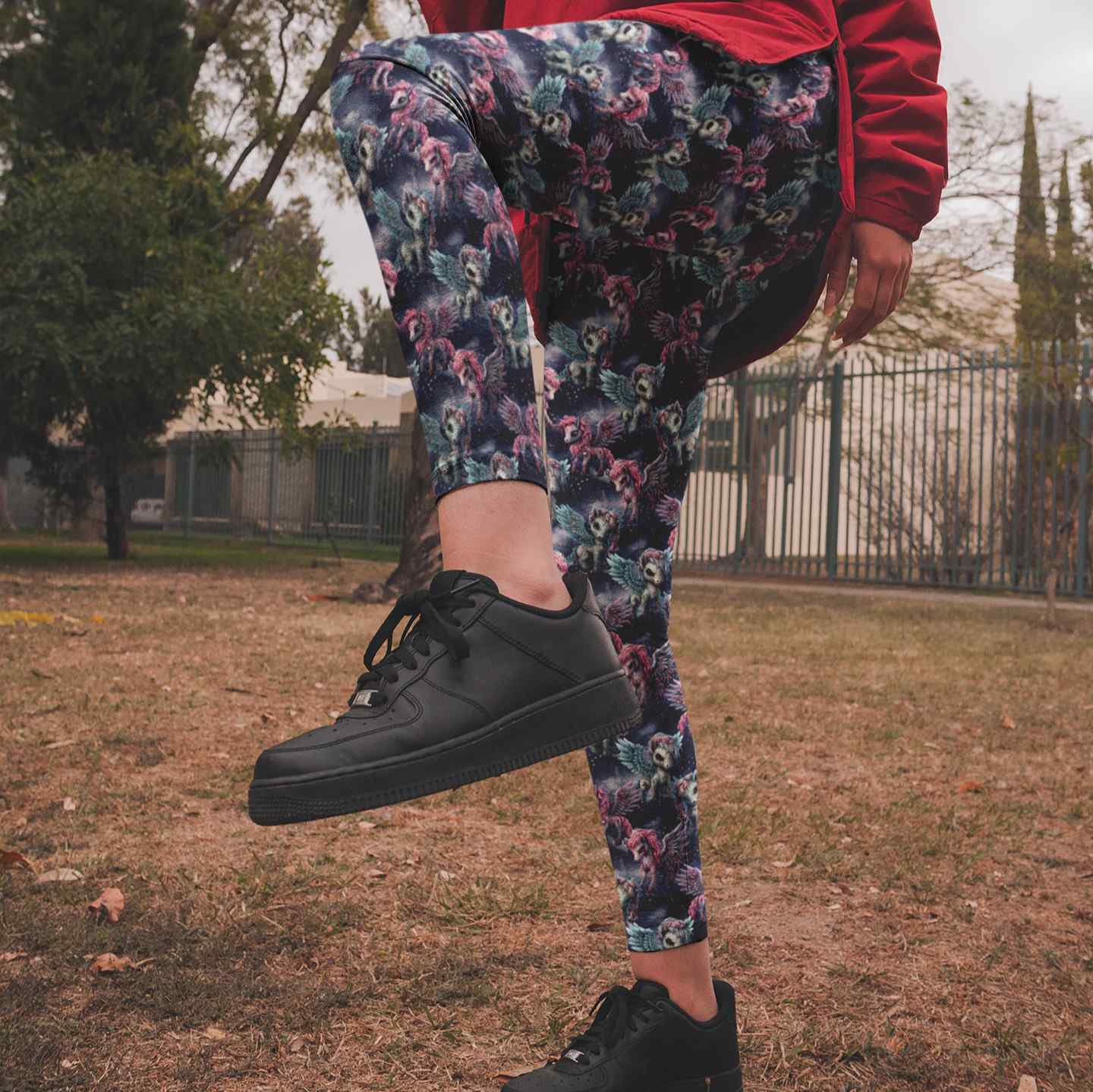 Person wearing black sneakers and zombie pegasus leggings in an outdoor setting