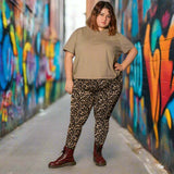 Person wearing a beige hoodie and leopard print pants standing in front of colorful graffiti walls.