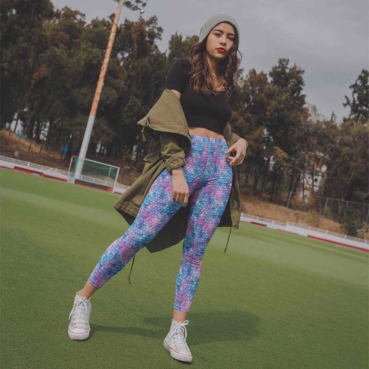 Woman in colorful leggings and black crop top standing on a sports field.