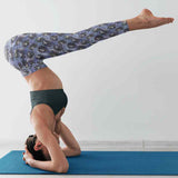 Person performing a yoga pose on a blue mat with a white wall background