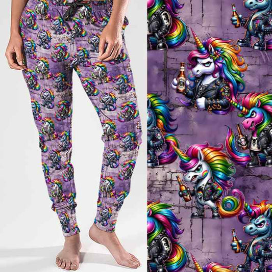 mockup of Full-length jogger pants with a bold print featuring punk-style unicorns with rainbow manes, leather jackets, studs and beer bottles. The background is a grungy purple brick wall for added edge.