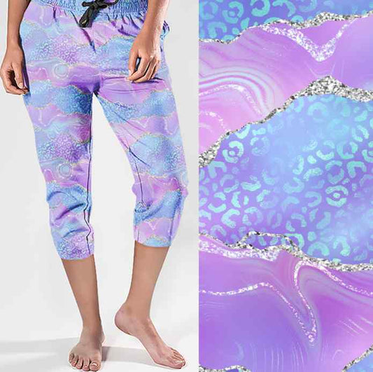 Capri joggers with wavy pastel pink and blue design, glitter accents, and leopard print; close-up shown